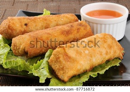 A plate of chicken egg rolls with sweet and sour sauce