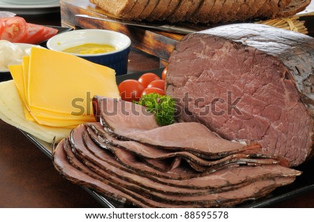 Thin sliced roast beef with cheeses, condiments and sliced rye bread for sandwiches