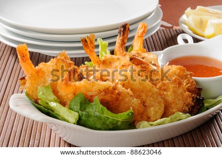 A platter of coconut shrimp with sweet sauce and lemon wedges