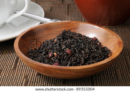 Whole leaf black pomegranate tea in a wooden sample bowl