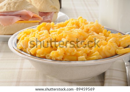 Bowl of macaroni and cheese with ham sandwiches on dinner rolls
