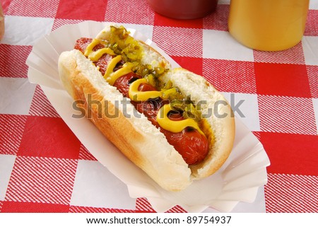 A hot dog with relish on a picnic table
