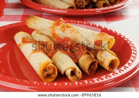 A plastic plate with steak and cheese taquitos topped with salsa