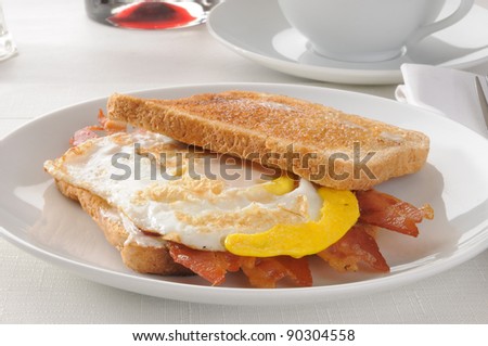 A bacon and fried egg sandwich on buttered toast