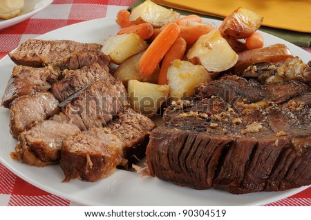 A sliced beef pot roast with autumn vegetables