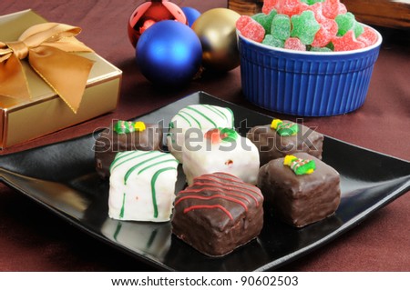 A plate of petit fours with Christmas decorations and star shaped gum drops