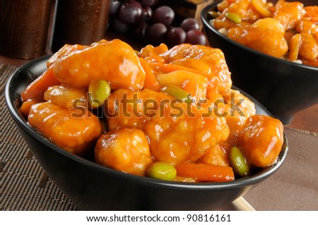 A bowl of orange chicken with chopsticks