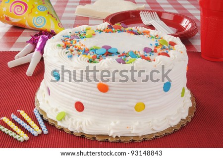 A birthday cake with party streamers, candles and plastic plates