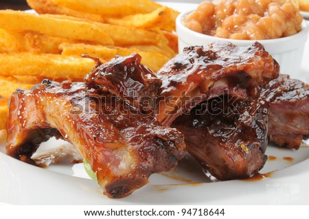 Close up of beef or pork ribs with fries and baked beans