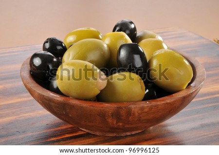 A wooden bowl of black and green olives stuffed with anchovies