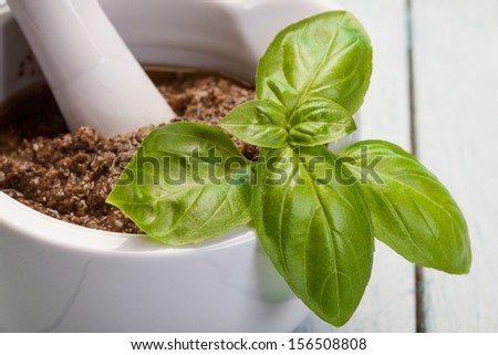 Basil pesto in a small bowl with fresh basil leaves