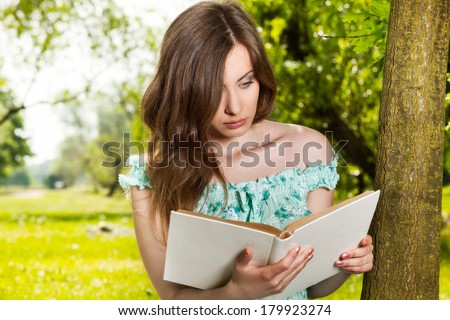 Young woman reading a book in spring park