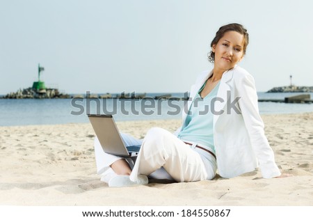 Businesswoman with laptop sitting on a beach in the sea coast