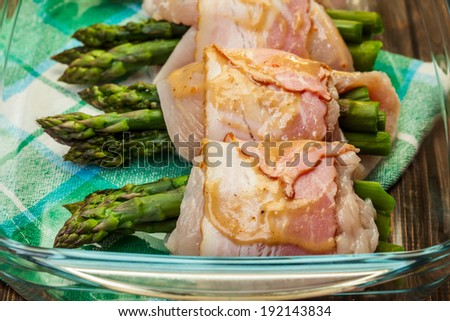 Fresh asparagus wrapped in chicken and bacon in a baking dish
