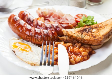 Full English breakfast with bacon, sausage, fried egg, baked beans and tea