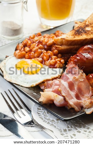 Full English breakfast with bacon, sausage, fried egg, baked beans and orange juice