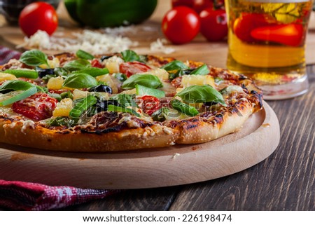 Pizza hawaii with beer served on cutting board
