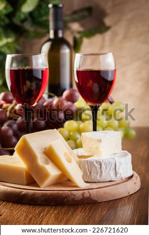 Cheese with a bottle and glasses of red wine on wooden table