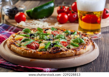 Pizza hawaii with beer served on cutting board