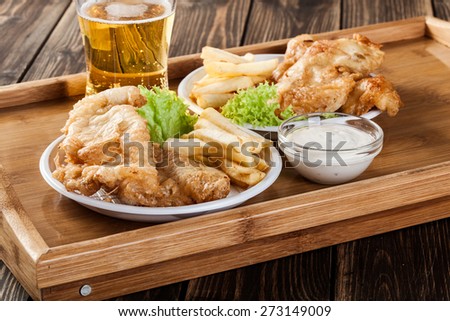Traditional fish and chips with tartar sauce on a tray