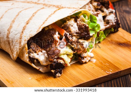 Tasty fresh wrap sandwich with beef, vegetables and tzatziki sauce