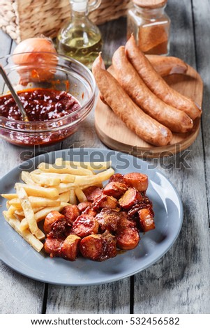 Traditional German currywurst - pieces of sausage with curry sauce and french fries. Top view