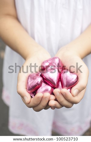 a girl holds pink foiled chocolate hearts in hands