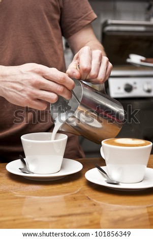 a barista pours milk to complete the coffee making process, this coffee is a \