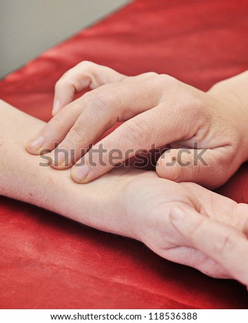 a medical practitioner checks her patient\'s pulse at the wrist
