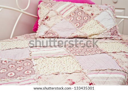 pink patchwork quilt on a bed, close up