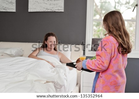 mum smiles as she receives breakfast in bed for mother\'s day