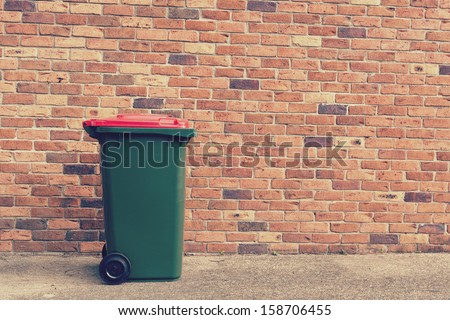 large wheelie bin in front of a brick wall