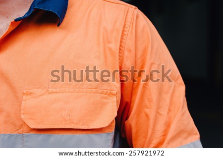 man\'s shoulder in hi vis workshirt with copyspace for logo
