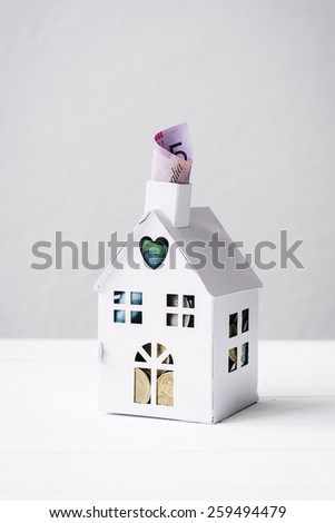 concept for saving for a house, mini house with $5 Australian, poking out