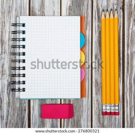 Open notebook with a pencil and an eraser on a wooden background