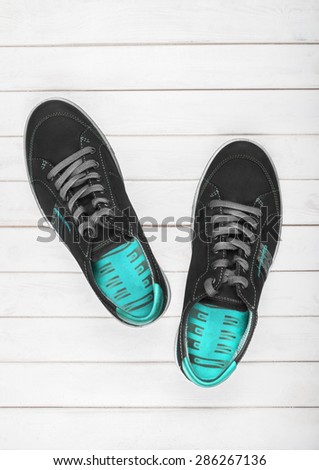 Black sneakers with blue lining on a white wooden background