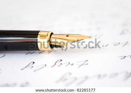 Selective focus on gold pen over hand written letter. Focus on tip of pen nib.