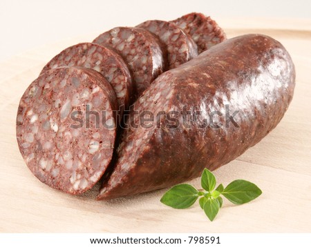 Blood sausage / blood pudding / black pudding with a piece of oregano in close-up.
