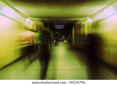 A motion blur abstract of a people walking. Tunnel. Cross process lighting.