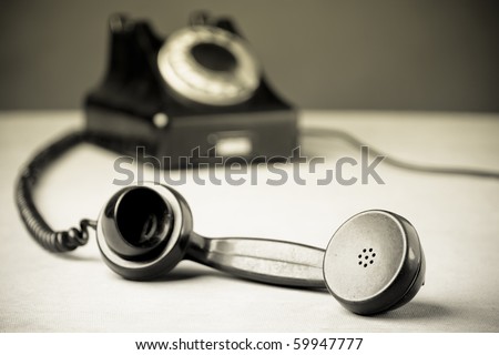 Vintage Rotary Dial Telephone. Old newspaper photo style. Soft focus with focus on handset.