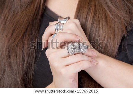 Closeup of the hands of a woman wearing multiple rings on her fingers with carefully manicured fingernails