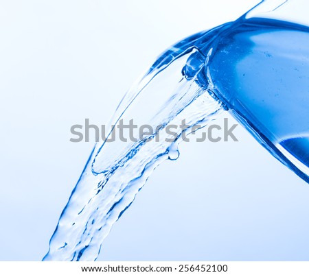 Cool Water Pouring from a Transparent Glass Cup, close up