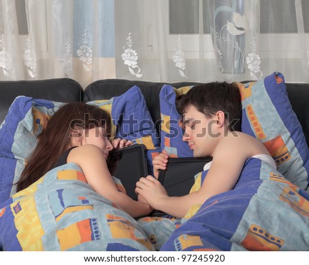 Young couple asleep in an embrace with a tablet laptop