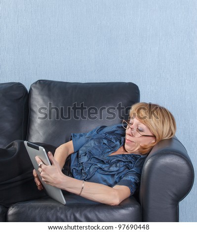 Portrait of relaxed middle aged woman using tablet PC on couch