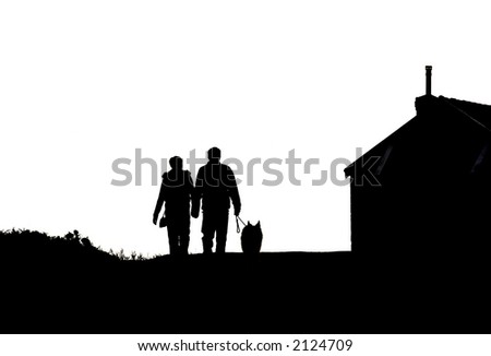 silhouette of a young couple walking a dog next to a house.