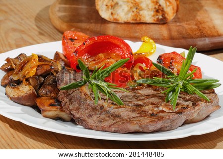 Grilled beef steak with mushrooms, peppers, tomatoes on a plate