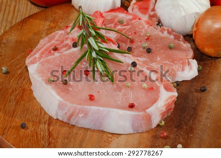 Raw pork chop on a wooden chopping board