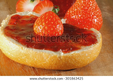 Bowl of strawberries, strawberry jam, bread with jam on a wooden board