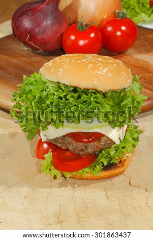 Hamburgers, fast food, burger, hamburger steak with salad, tomato, cheese, cucumber on a wooden chopping board