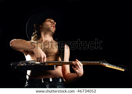 Rock\'n\'roll young man playing guitar. Black background. Studio shot.